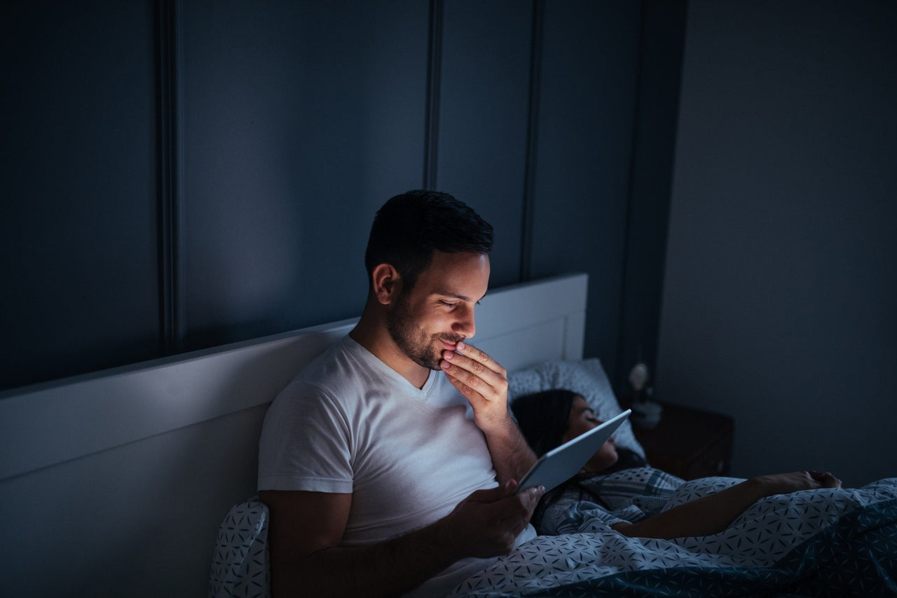 man who can't sleep using tablet at night in bed
