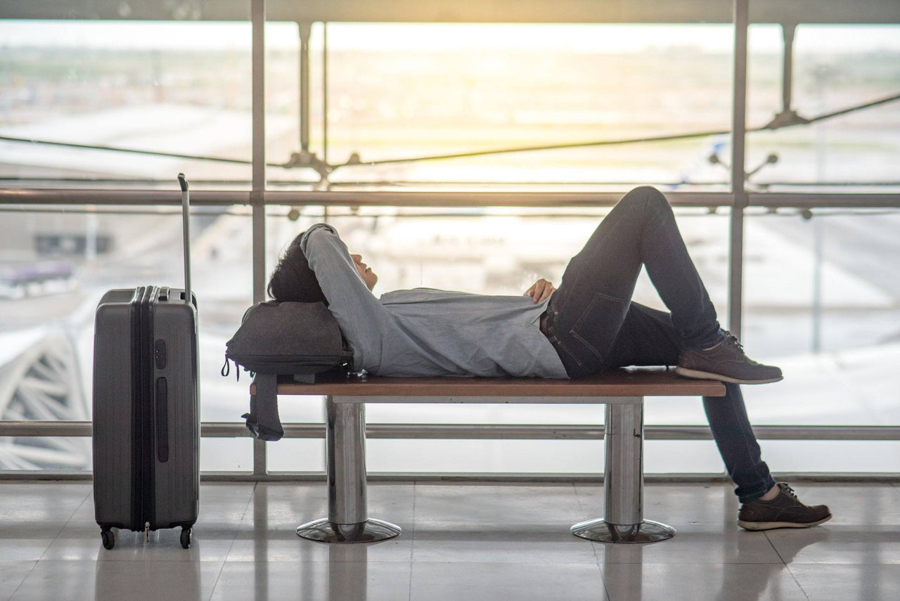 person sleeping in an airport on a bench