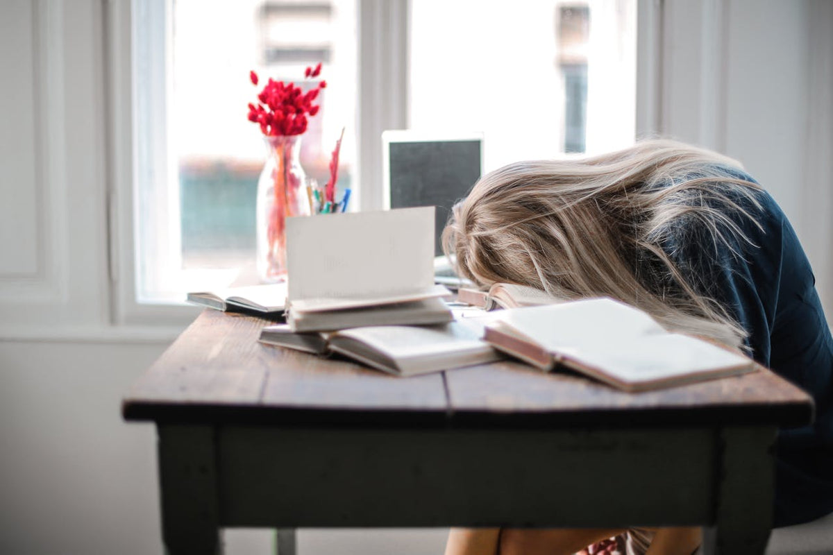 Exhausted woman putting head down in books