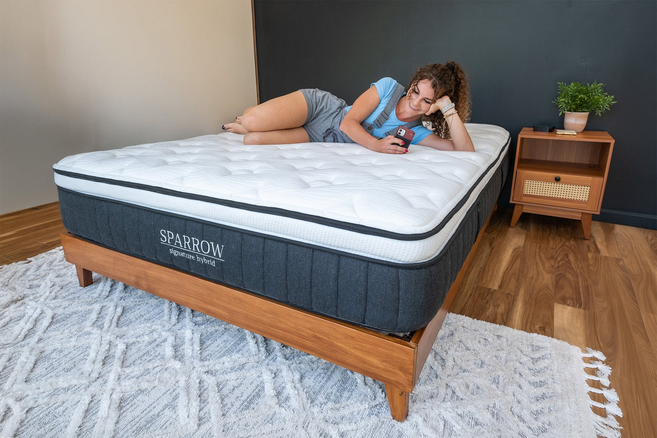 a woman laying on a sparrow mattress and woodland redwood grove platform bed frame