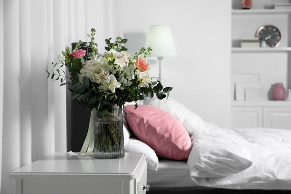 A vase of flowers set aside a comfy bed