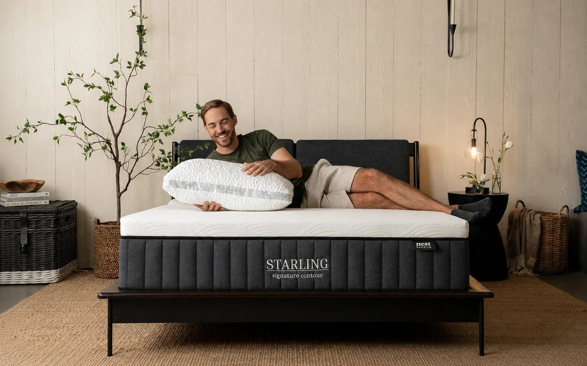 a man laying across the starling mattress with a pillow in his arms