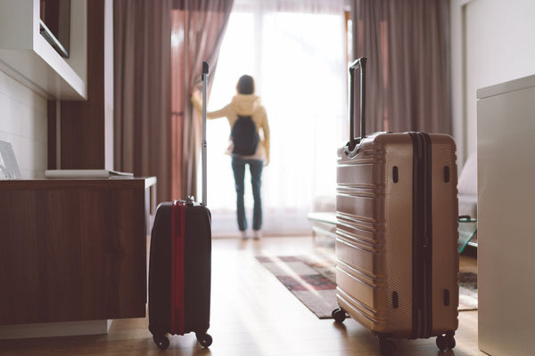 suitcases in hotel room blurred traveler looking out window