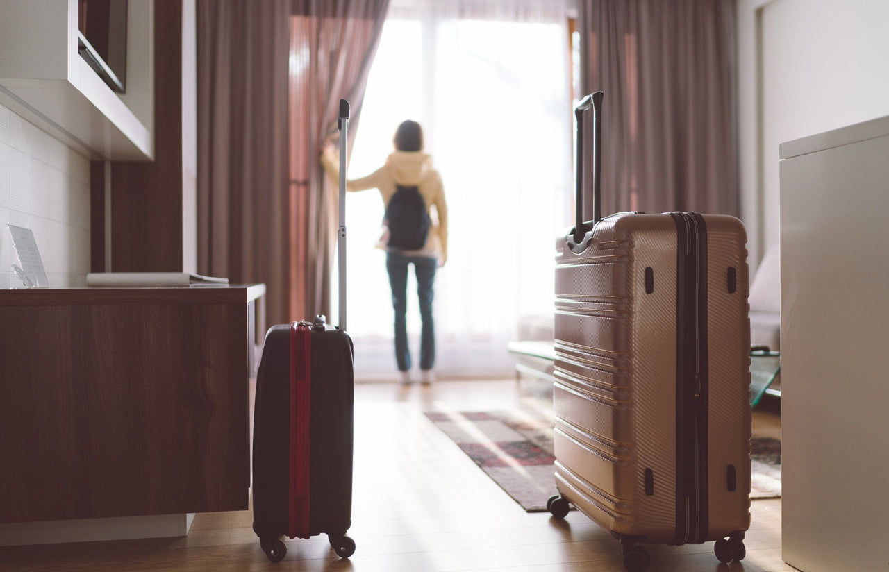 suitcases in hotel room blurred traveler looking out window