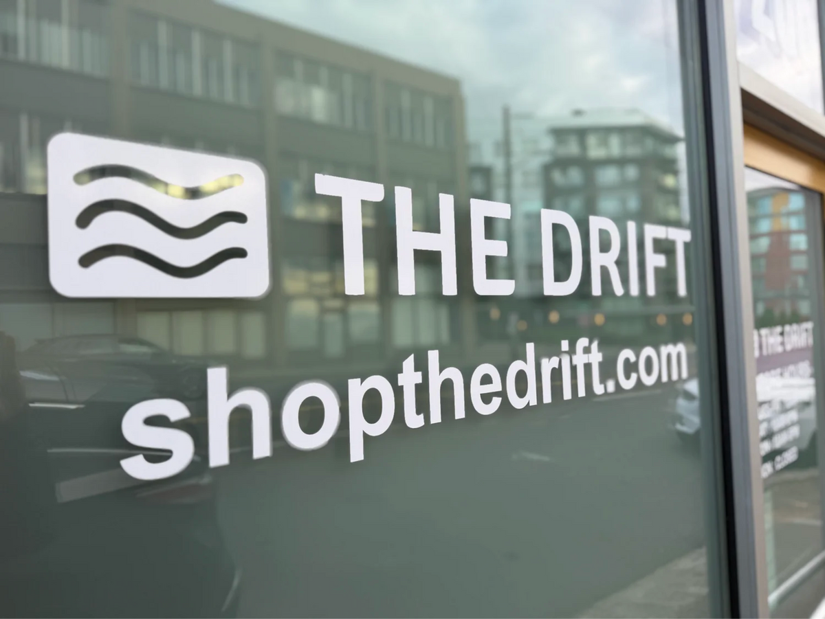 Glass storefront window with 'The Drift' logo and website text