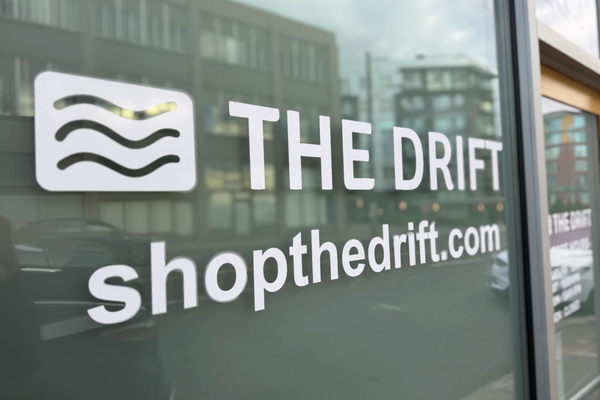 Glass storefront window with 'The Drift' logo and website text