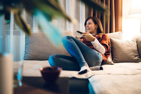 woman holding remote and watching tv before bed