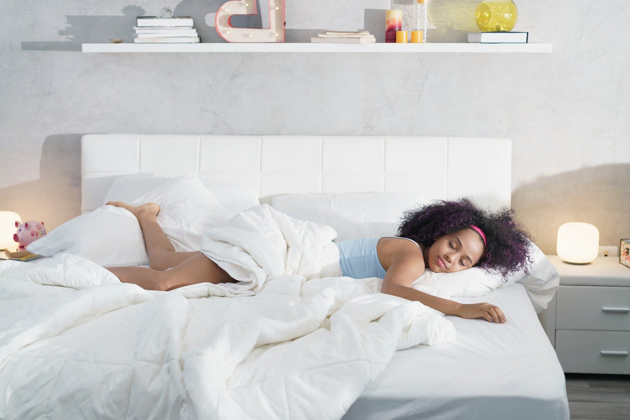 woman lounging across bed with extra set of sheets