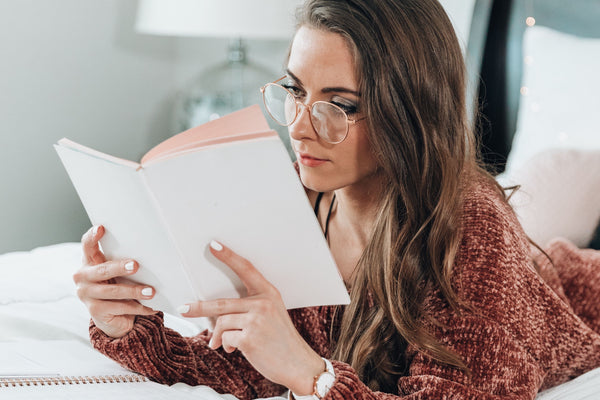 woman reading journaling in bed