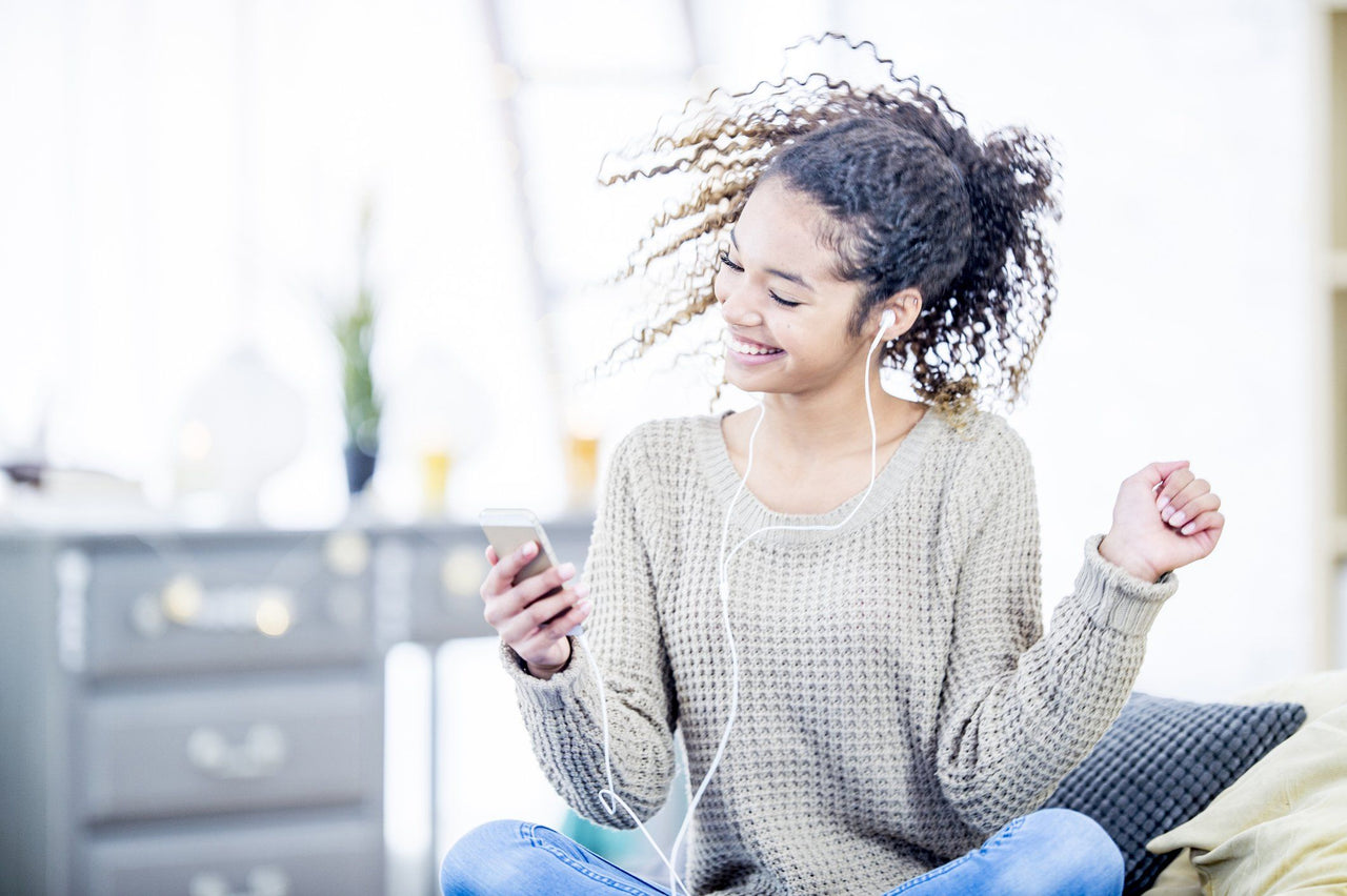 woman relieving stress by listening to music and dancing in bedroom