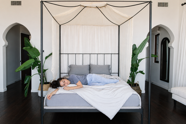 A woman lying comfortably on Nest Bedding sheets and a mattress