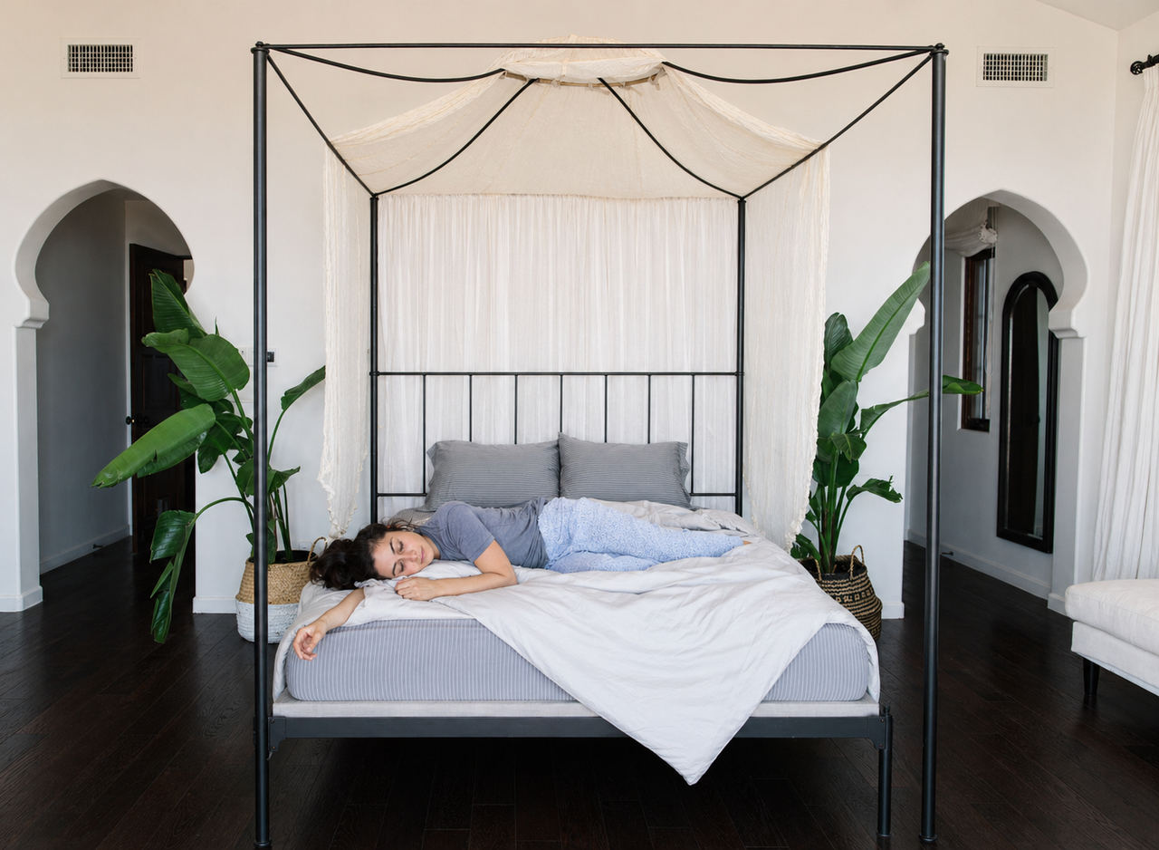 A woman lying comfortably on Nest Bedding sheets and a mattress