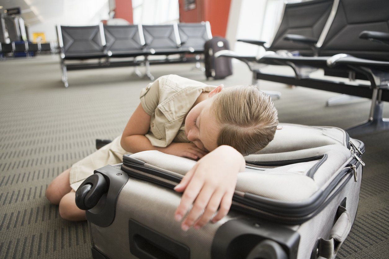 woman sleeping on suitcase in airport