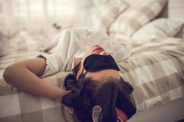 woman sleeping upside down in bed with eye mask