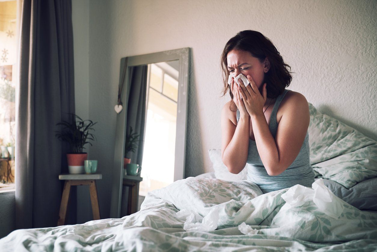 woman sneezing in bed with allergies