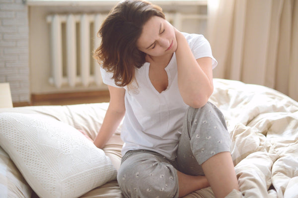 woman waking up with sore neck from poor sleeping position