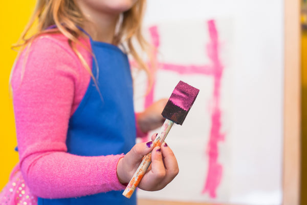 young girl painting with sponge brush