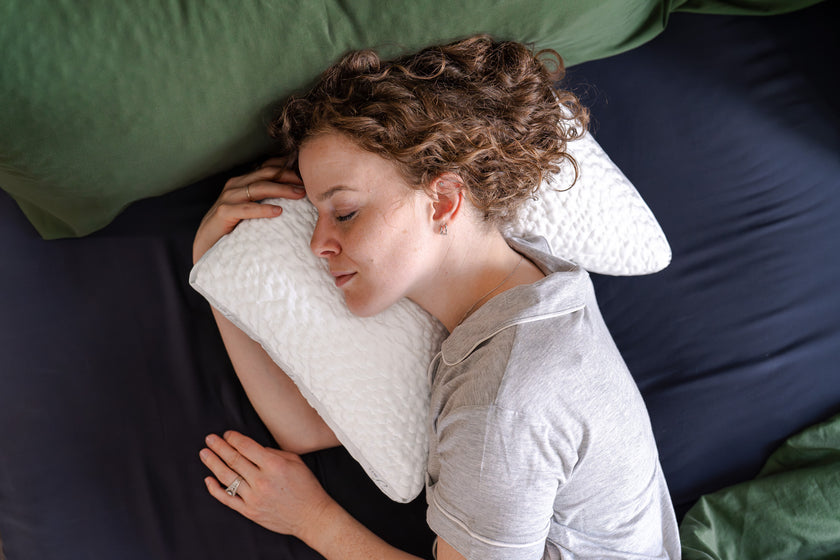 Woman laying on her side in bed while resting her head on an easy breather jr side sleeper pillow
