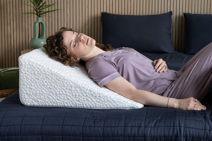 Woman comfortably lying on an easy breather wedge-shaped pillow in bed.