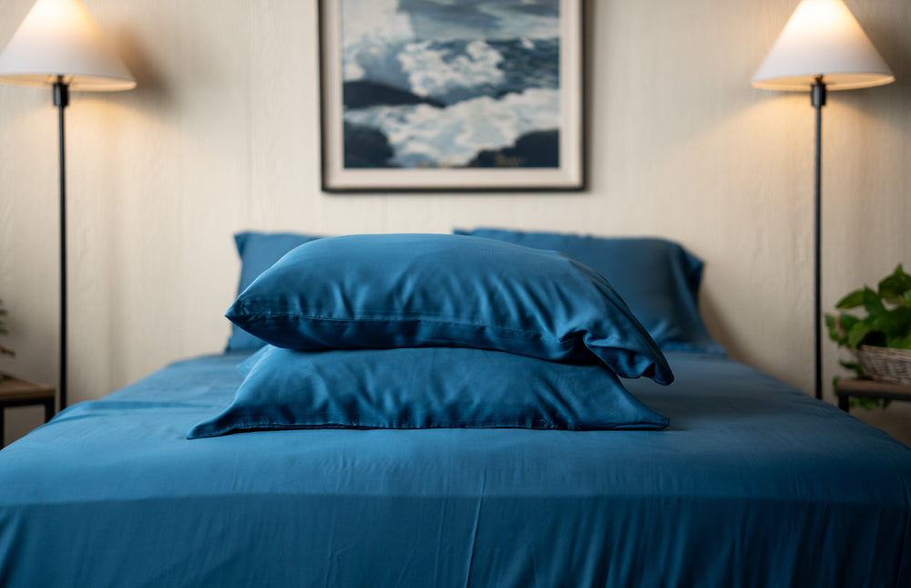 two stacked pillows at the foot of a bed encased in the nest bedding bamboo indigo blue pillowcases
