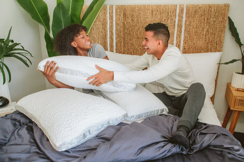 a couple in bed fighting over who will get to sleep with the new pillow